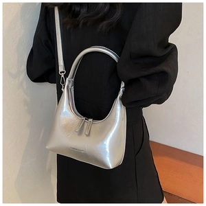 Close-up of silver metallic underarm bag showing dual zippers and brand lettering detail