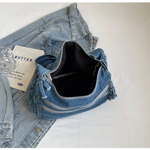 Top view of blue denim tote bag showing multiple zipper compartments and inner lining