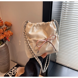 Detail of silver bucket backpack with a pink bow and metallic chain strap