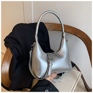 Chic silver metallic hobo bag with sleek buckle detail placed on a wooden chair