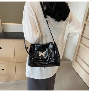Silver butterfly chain shoulder bag worn by model in a cozy interior setting