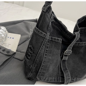 Detail of dark denim shoulder bag featuring contrast stitching and practical side pocket