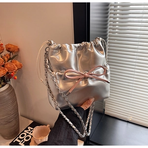 Detail of silver metallic bucket backpack with pink bow and drawstring chain strap