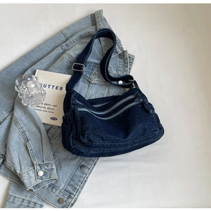 Dettaglio della borsa a tracolla in denim blu scuro con multitasche e tracolla regolabile