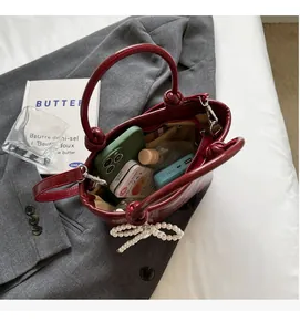 Détails de l'intérieur du sac bordeaux montrant l'espace pour téléphone et maquillage