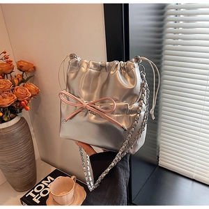 Close-up of silver bucket bag with pink bow detail and metallic chain strap