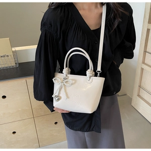 Détail du sac seau en cuir blanc crème avec nœud en perles et logo embossé