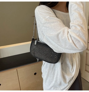 Detail of a black baguette bag with sparkling rhinestones and a silver metal chain strap