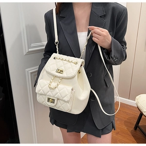 Detail of white quilted leather backpack with gold chain straps and twist-lock closure