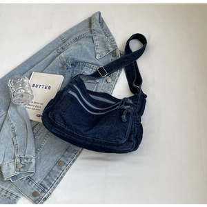Detail of dark blue denim crossbody bag with multiple zippers and wide adjustable strap