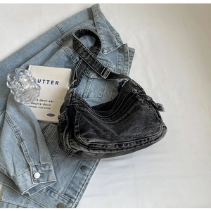 Detail of black washed denim hobo bag featuring adjustable wide strap and metal hardware