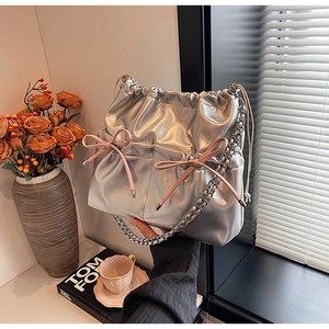 Close-up of a silver drawstring backpack with pink bows and woven metal chain straps