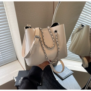 Close-up of cream white bucket bag featuring glossy leather texture and silver chain strap