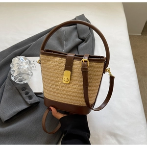 Detail der gewebten Stroh-Eimertasche mit dunkelbraunem Lederboden und Gold-Drehverschluss