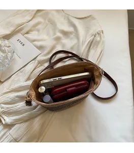 Detailed interior of woven straw crossbody bag showing space for phone and wallet
