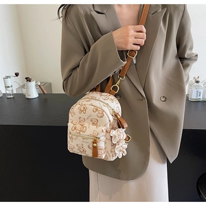 Mini sac à dos en cuir crème avec motifs ours et charm assorti porté par un mannequin