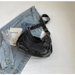 Dettaglio borsa a tracolla in denim nero lavato con cerniere e decorazione nappa