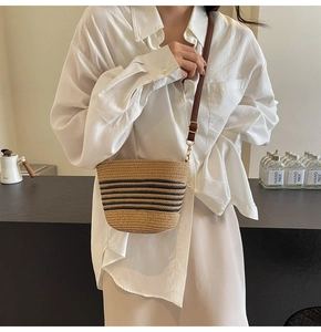 Detailed close-up of a woven straw bucket bag with black stripes on a white shirt model