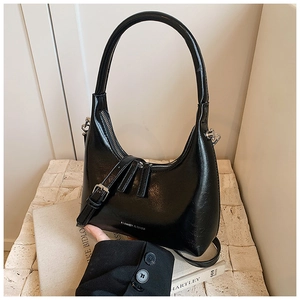 Detailed macro view of black patent leather hobo bag texture and silver metal buckle