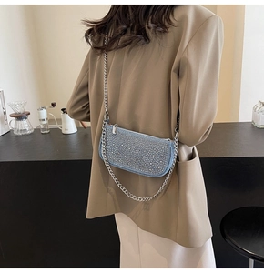 Close-up of sparkling rhinestone handbag with silver metal chains and light blue fabric