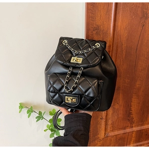 Close-up of quilted black leather backpack with gold chain and twist-lock hardware