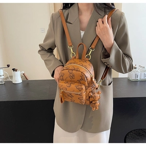 Gros plan d'un mini sac à dos marron avec motifs d'ours et son petit pendentif en peluche