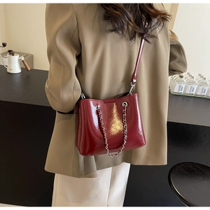 Detail of red patent leather bucket bag with silver chain handle in casual setting
