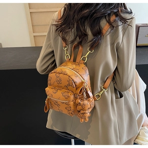 Vue détaillée du dos d'un mini sac à dos en cuir marron avec imprimé ours et breloque
