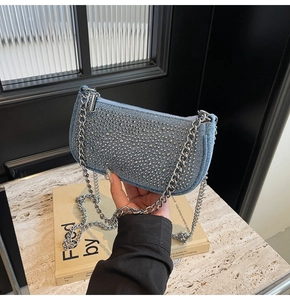 Detail of blue denim shoulder bag with silver studs and thick metal chain strap