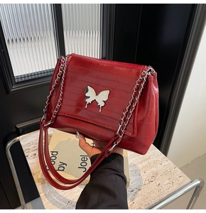 Close-up of red oil-wax leather shoulder bag with crocodile pattern and butterfly buckle