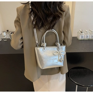 Détail du sac seau métallisé argent avec nœud en perles et breloques cœur avec longue bandoulière