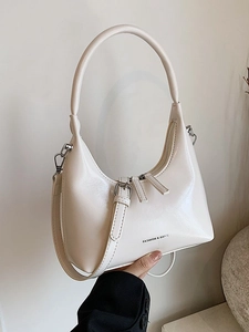 Creamy crescent underarm bag with a decorative buckle strap and top handle