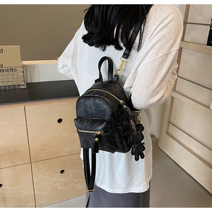 Détail d'un mini sac à dos noir avec gaufrage d'ours, zip doré et breloque peluche