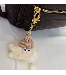 Detail of a plush monster bag charm with a brown knit hat on a dark bear backpack