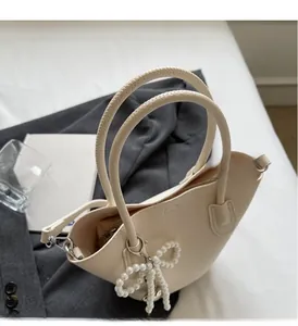 Macro detail of cream bucket bag showing lychee grain texture and pearl bow charm