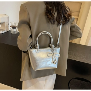 Détail du sac seau argenté avec poignée à double nœud et breloque nœud en perles