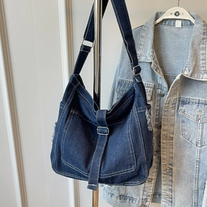Retro denim shoulder bag in dark blue with white stitching and metal buckle accents