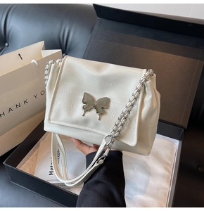 Detail of cream faux crocodile texture handbag with silver butterfly buckle and chain strap