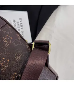 Detail of brown leather bag with bear print, nylon strap and golden metal buckle