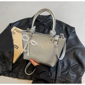 Sac à main argenté métallisé avec nœud en perles et logo de marque en relief