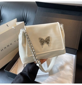 Close-up of a white crocodile texture bag with a silver butterfly buckle in a gift box