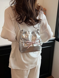 Silver metallic bucket backpack with pink bow detail and chain straps for women