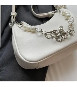 Close-up of white crescent bag showing pearl chain and butterfly metal pendant detail
