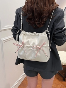 Silver metallic drawstring backpack with pink bow detail and chain straps on model