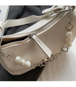 Close-up of a white PU leather shoulder bag with smooth zipper and pearl flower chain