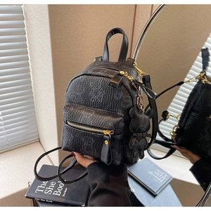 Détail d'un mini sac à dos noir avec motifs d'ours embossés et pendentif ours en peluche