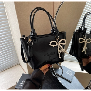 Détail du sac seau noir en cuir brillant avec poignée nouée et breloque en perles
