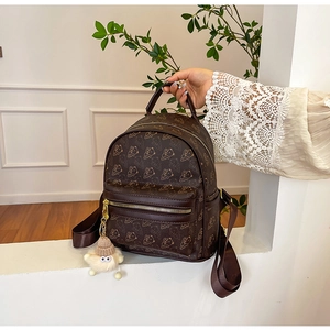 Detail of a brown mini backpack featuring cute bear prints and gold-tone zippers