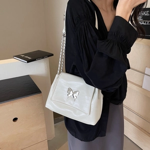 Silver shoulder bag with crocodile texture and metal butterfly detail on chain strap