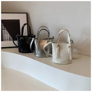 Close-up of mini bucket bags in black, silver, and beige with textured leather and metal strap details